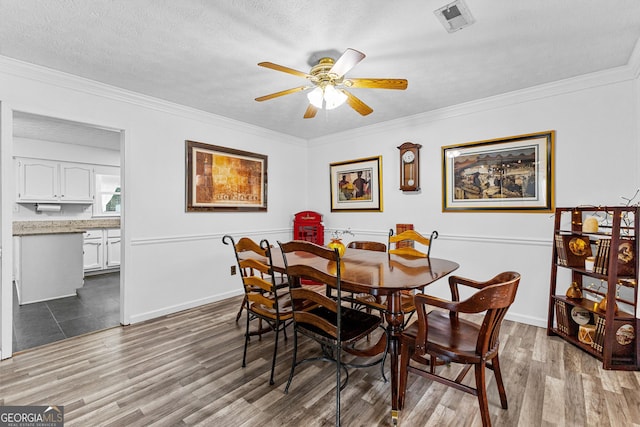 dining room featuring a textured ceiling, ornamental molding, hardwood / wood-style floors, and ceiling fan