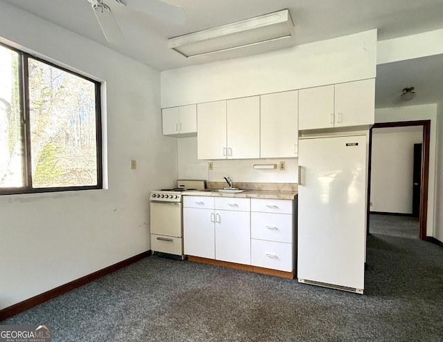 kitchen with white appliances, dark carpet, and white cabinets