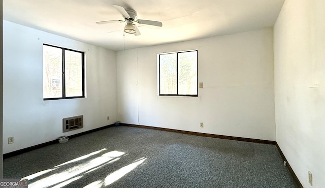 unfurnished room featuring heating unit, dark carpet, and ceiling fan