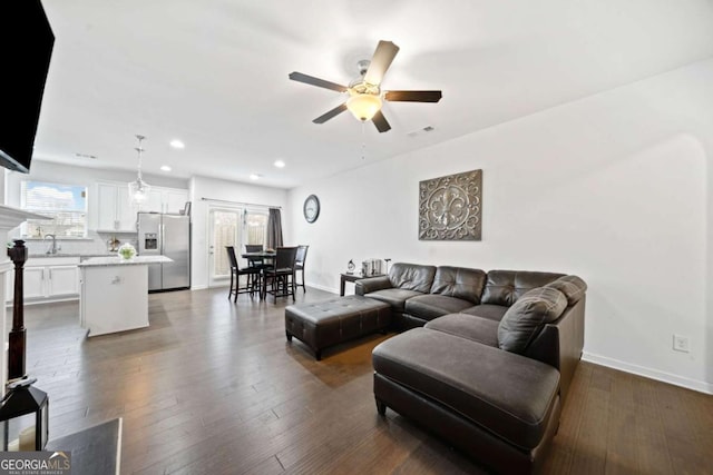 living room featuring ceiling fan, sink, and dark hardwood / wood-style floors