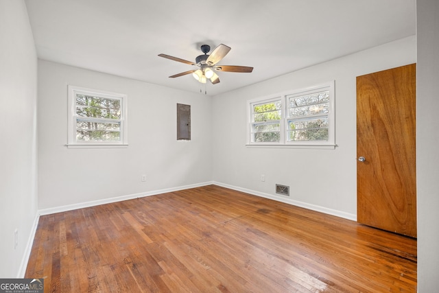 empty room featuring ceiling fan, plenty of natural light, and wood-type flooring