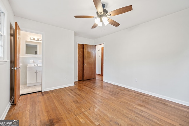 unfurnished bedroom with light wood-type flooring, sink, connected bathroom, and ceiling fan