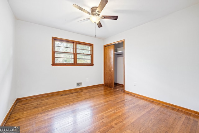 unfurnished bedroom with ceiling fan, a closet, and wood-type flooring