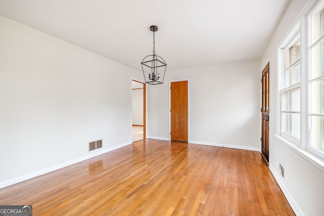 spare room with light hardwood / wood-style flooring and a chandelier