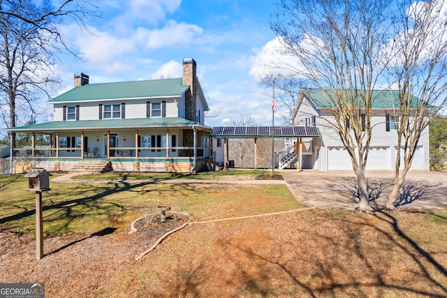 farmhouse inspired home with a chimney, concrete driveway, metal roof, a garage, and a front lawn