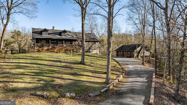 view of front of property featuring covered porch, a chimney, and a front lawn