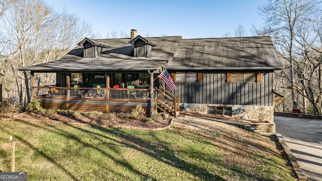 rustic home with a porch, a chimney, and a front lawn