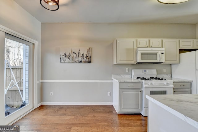 kitchen with white appliances, light wood-type flooring, and baseboards