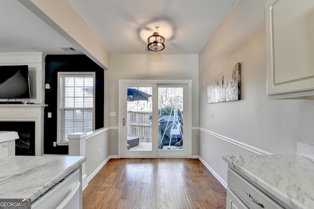 doorway to outside featuring light wood-type flooring, baseboards, a fireplace, and visible vents