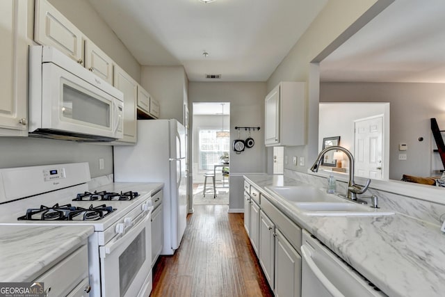 kitchen featuring white appliances, dark wood-type flooring, a sink, visible vents, and white cabinetry