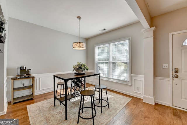 dining room with visible vents, wainscoting, light wood finished floors, and ornate columns