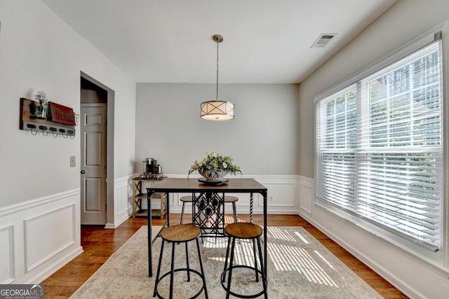 dining room featuring a wainscoted wall, visible vents, and wood finished floors