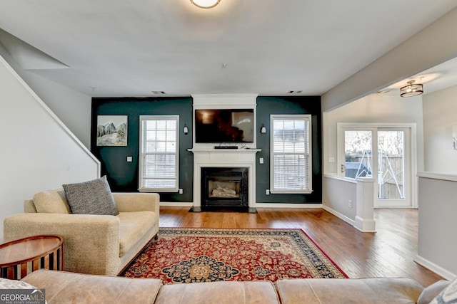 living area featuring visible vents, a glass covered fireplace, light wood-style flooring, and baseboards