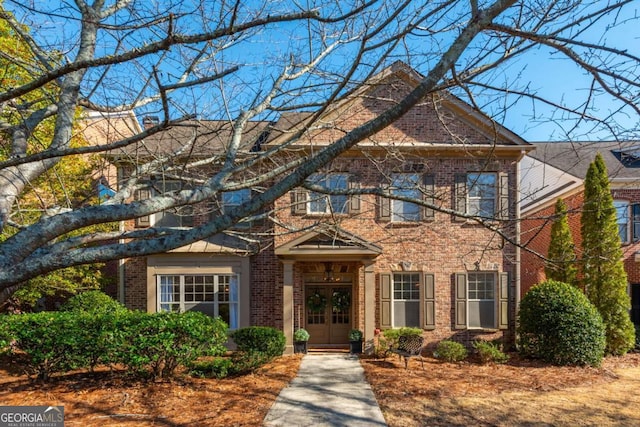 colonial inspired home with brick siding and french doors