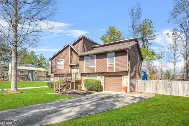 view of front of house with a front lawn, concrete driveway, fence, and stone siding