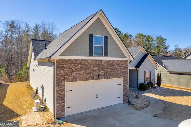 view of front of home with a garage, stone siding, concrete driveway, and roof with shingles