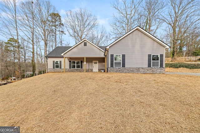 view of front of property featuring stone siding and a front lawn