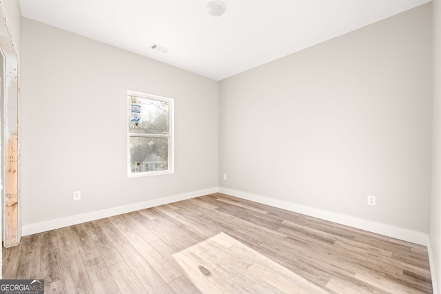 spare room with light wood-style floors, visible vents, and baseboards