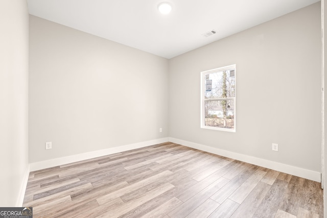 unfurnished room featuring light wood finished floors, visible vents, and baseboards