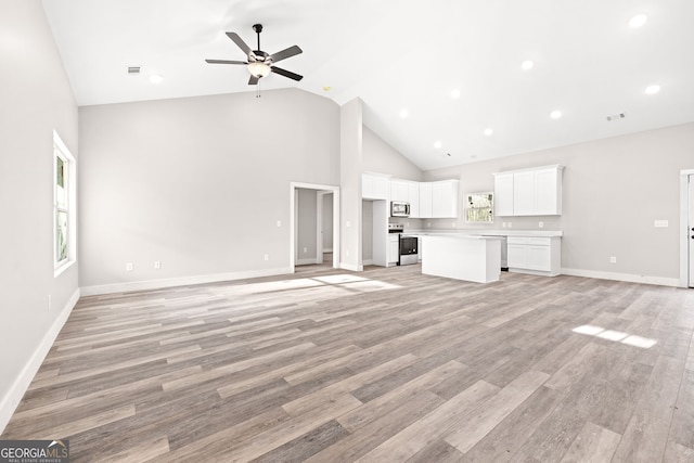 unfurnished living room featuring light wood finished floors, ceiling fan, high vaulted ceiling, and baseboards