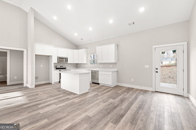 kitchen featuring white cabinets, a center island, stainless steel appliances, light countertops, and light wood-style floors