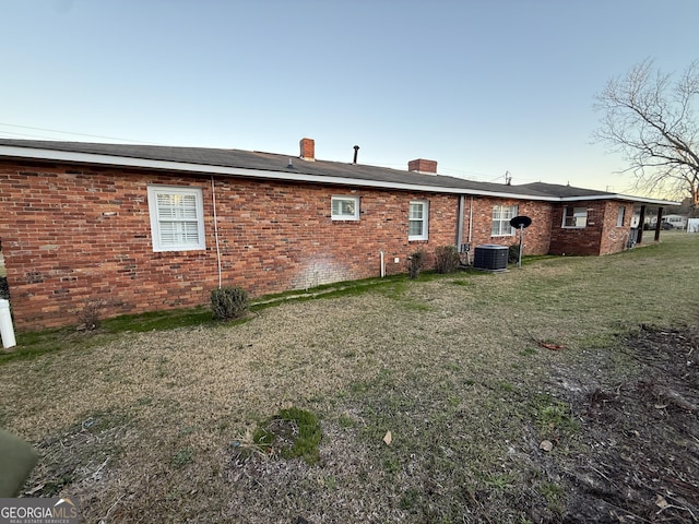 back of property with central AC unit and a yard