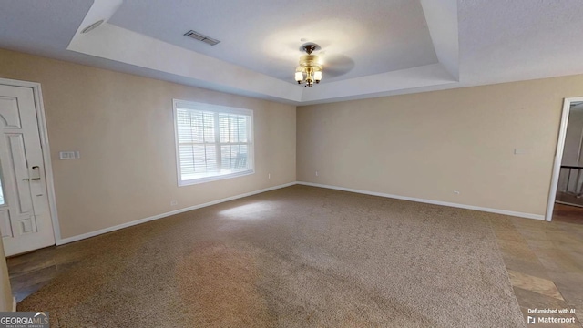 carpeted spare room featuring a tray ceiling