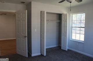 unfurnished bedroom with ceiling fan, a closet, and baseboards