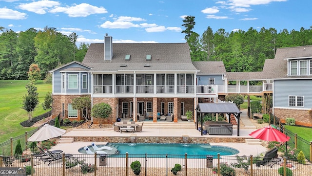 rear view of house with a swimming pool with hot tub, a sunroom, pool water feature, and a patio