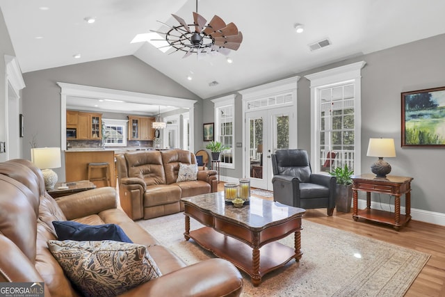 living room with light hardwood / wood-style flooring, french doors, vaulted ceiling, and ceiling fan