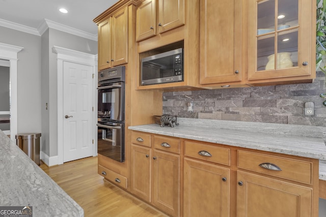 kitchen with light stone countertops, decorative backsplash, crown molding, and double oven