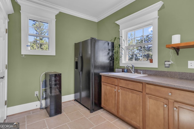 kitchen with plenty of natural light, crown molding, black fridge with ice dispenser, and sink