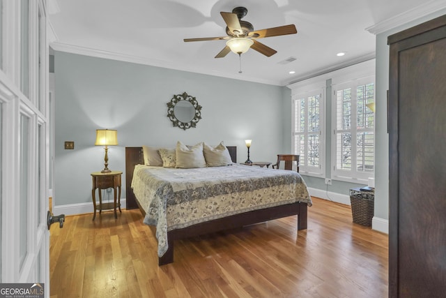 bedroom featuring hardwood / wood-style floors, ornamental molding, and ceiling fan