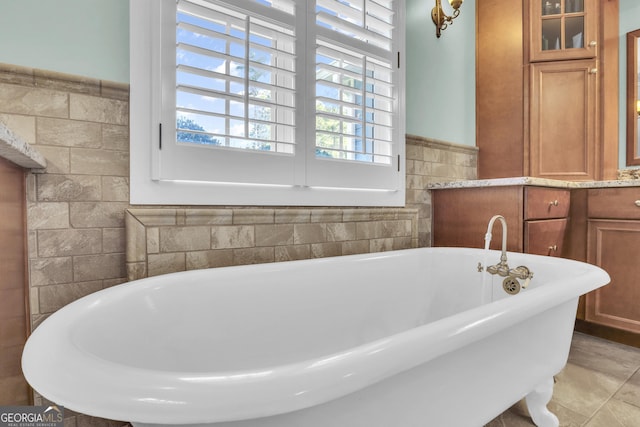 full bath featuring a freestanding bath, tile patterned flooring, and tile walls