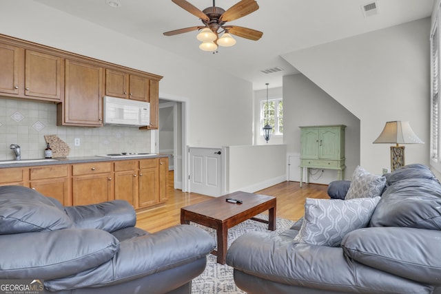 living room featuring ceiling fan, sink, and light hardwood / wood-style floors