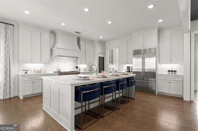 kitchen with stainless steel appliances, dark wood-style flooring, white cabinetry, light countertops, and custom range hood