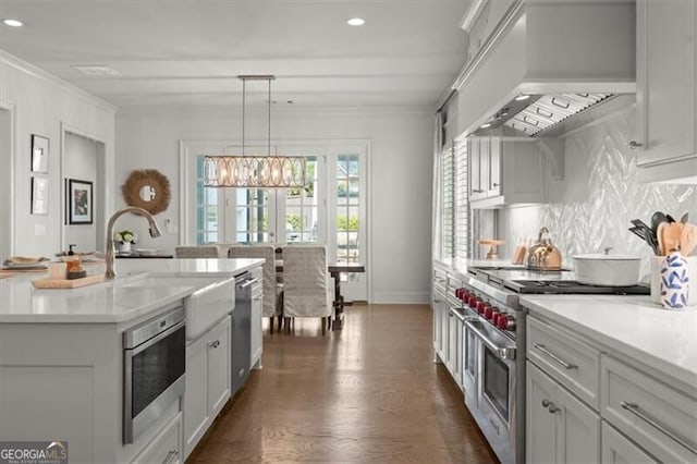 kitchen featuring appliances with stainless steel finishes, custom exhaust hood, light countertops, and ornamental molding