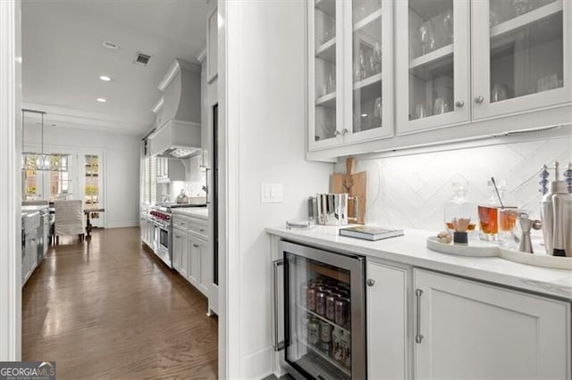 bar with beverage cooler, premium range hood, decorative backsplash, dark wood-style floors, and stainless steel range