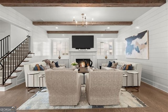 living room with stairs, a warm lit fireplace, plenty of natural light, and wood finished floors