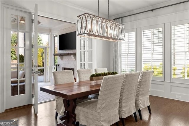 dining room with crown molding, a fireplace, a decorative wall, and wood finished floors