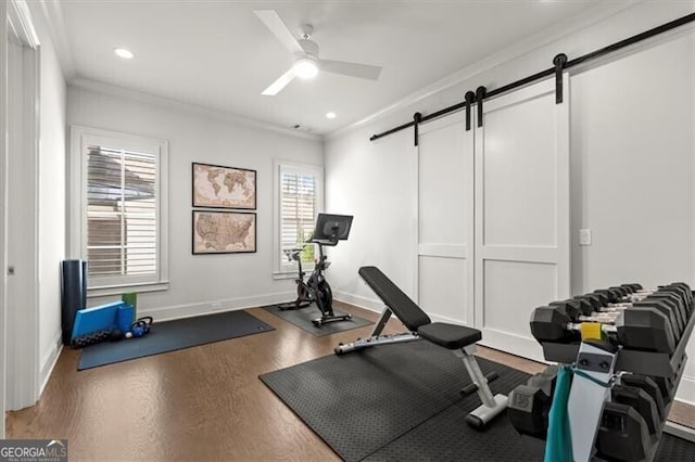 workout room featuring crown molding, a barn door, a ceiling fan, wood finished floors, and baseboards