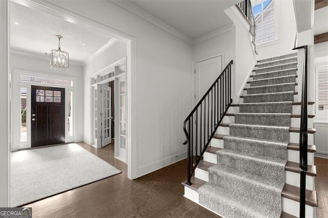 entryway with baseboards, a healthy amount of sunlight, wood finished floors, and crown molding