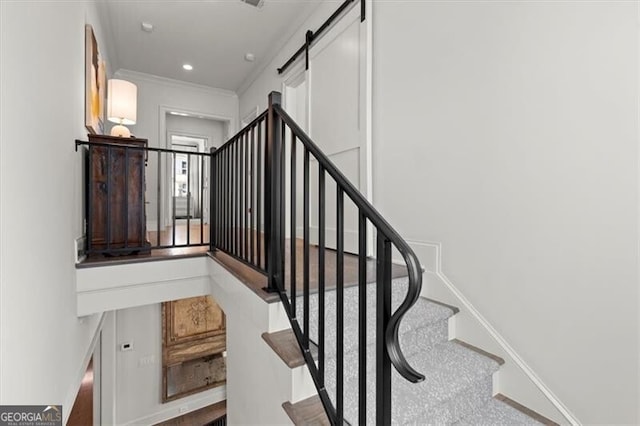 stairway featuring a barn door, baseboards, ornamental molding, and recessed lighting