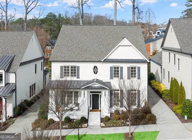 view of front of property featuring roof with shingles, a standing seam roof, metal roof, a residential view, and driveway