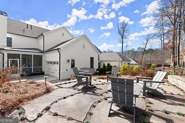 back of property with concrete driveway, an attached garage, a sunroom, a patio area, and fence