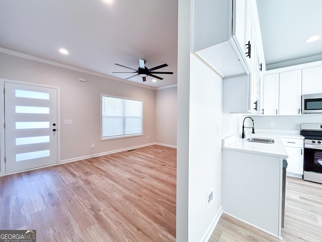 kitchen featuring light countertops, stainless steel appliances, ornamental molding, a sink, and white cabinetry