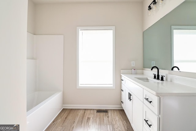 full bathroom with visible vents, wood finished floors, a healthy amount of sunlight, and vanity