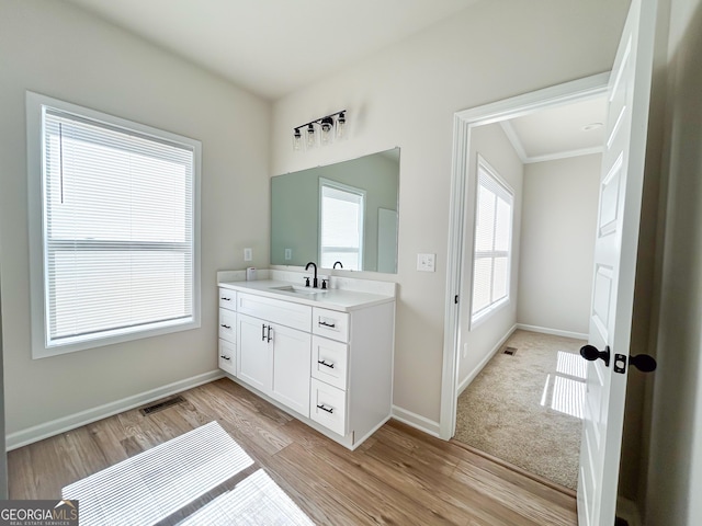 bathroom with baseboards, visible vents, vanity, and wood finished floors