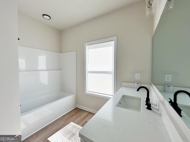 bathroom featuring vanity, a bath, and wood finished floors