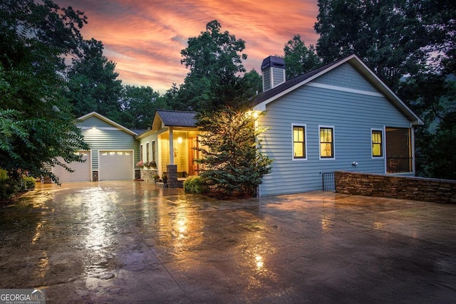 view of front of property featuring a garage, a chimney, and driveway